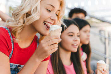 Obraz na płótnie Canvas Beautiful teenager, girl eating tasty ice cream, dessert on the street, sitting meeting with friends