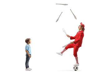 Boy watching a man in a red suit standing on a football and juggling