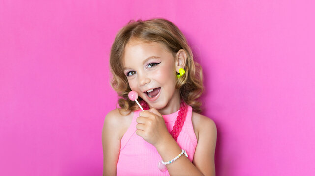 Cute girl with makeup in pink clothes, image in the style of Barbie. Trend for girls, portrait on the background