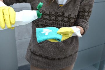 woman wearing gloves cleaning and disinfecting the toilet and bidet in a home bathroom