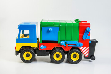 Multi-colored plastic toy trucks for children's games on a white background. Garbage truck.