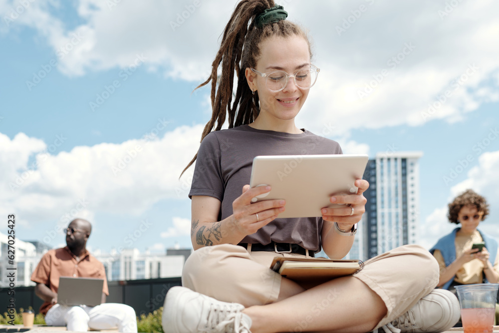 Aufkleber happy young female student or employee looking at tablet screen while watching online video or worki