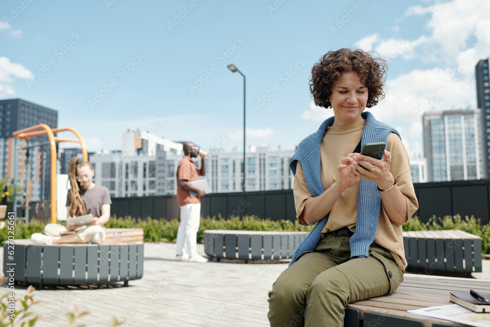 Aufkleber young smiling brunette female white collar worker scrolling in smartphone or watching online video w