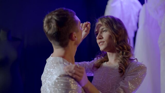two gays in wedding gowns dancing in dark studio and flirting, romantic date of homosexual couple