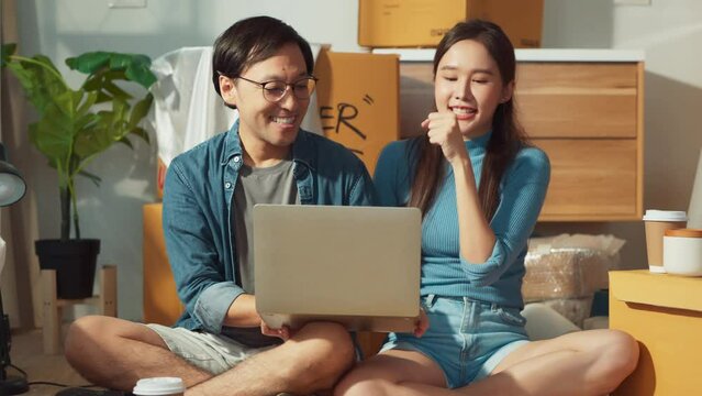 home moving take a break relax asian marry lover couple using laptop while singing song along together after resting from home moving uapack cardboard box in a new home living room area house moving