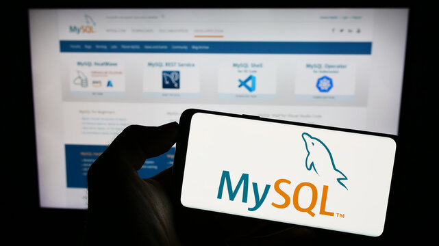 Stuttgart, Germany - 07-13-2023: Person holding cellphone with logo of relational database management system MySQL on screen in front of webpage. Focus on phone display.