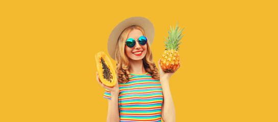 Summer portrait of happy cheerful smiling young woman with pineapple and papaya wearing straw hat,...