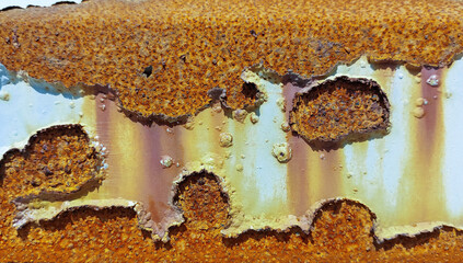 A fragment of the surface of an oil tank that has lost its protective white epoxy-polyurethane coating and is very heavily corroded.