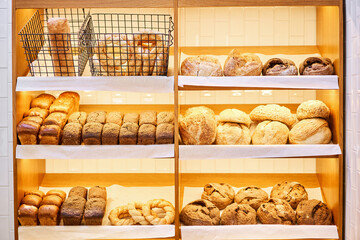 Different kinds of bread on the counter in the bakery shop. Fresh bread counter. Modern bakery with...