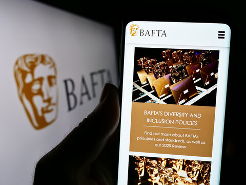 Stuttgart, Germany - 07-14-2023: Person holding cellphone with webpage of British Academy Film Awards (BAFTA) on screen in front of logo. Focus on center of phone display.
