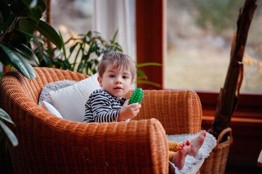 Little toddler boy having rest covered himself in blue pleid in straw chair