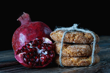 Shortbread cookies and opened pomegranate on a dark background...