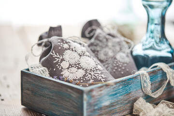 Sachets with embroidery filled with lavender on wooden background