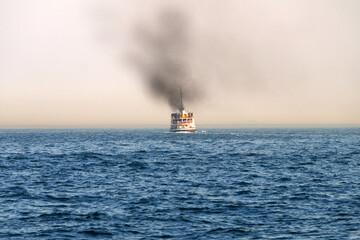 passenger ship on a clear sea horizon with black smoke from the chimney