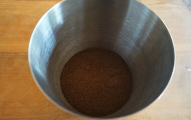 Braunes Kaffeepulver in silberner Metalldose auf Holztisch