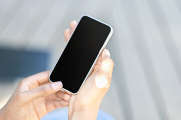 Cropped of black woman hands using smartphone, blurred outdoor background