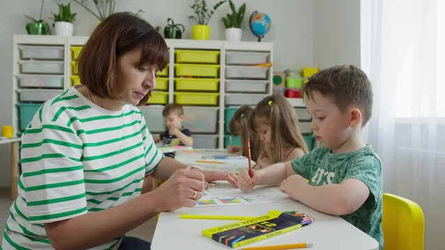 The teacher explained the task to one boy and is looking to see if anyone else needs help. Creative developmental tasks with elements of drawing. High quality 4k footage