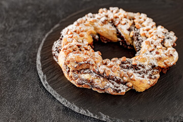 Brezel handcrafted sweet, pastry delicious snack, on slate stone plate round, dark background, selective focus .