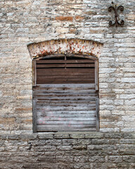 An old brick abandoned house with boarded up wooden weathered rusty windows without glass. The ruins of the old city and abandonment.