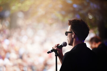 Charismatic frontman. A singer performing on stage at an outdoor music festival.