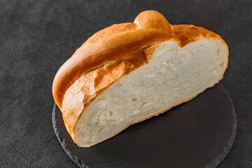 Bread loaf light round cut, on slate stone plate round, dark background, selective focus