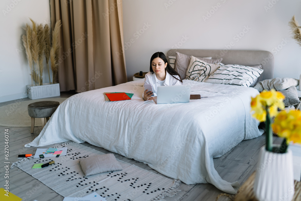 Poster young female using smartphone during break from working on netbook