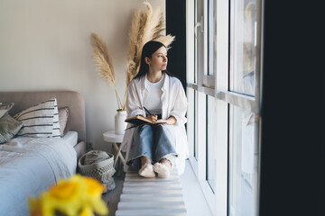 Pensive woman with notebook near window