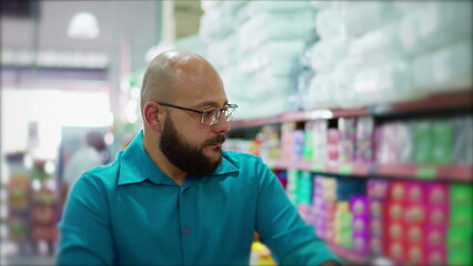 Consumer Maneuvering Shopping Cart through Supermarket Aisle, Selecting Goods for Purchase at Local Store