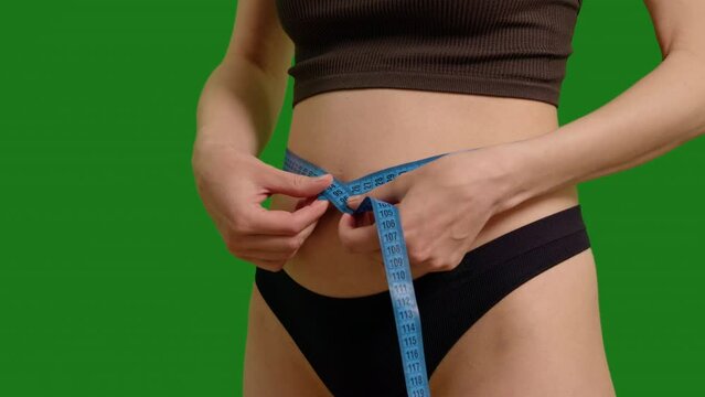 Pregnant woman measuring her belly against green screen background. Early pregnancy video shot while keeping track of weight and mesurements.