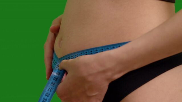 Extreme close up of early pregnancy abdomen shot keeping track of weight and mesurements on green screen background. Woman gaining weight during pregnancy.