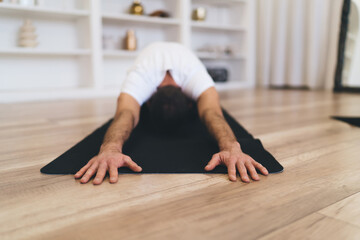 Anonymous man sitting in yoga pose on floor