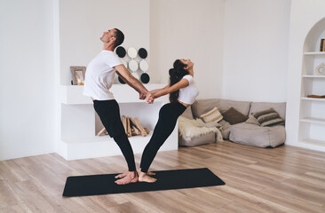 Obraz premium Sporty couple practicing yoga in spacious living room