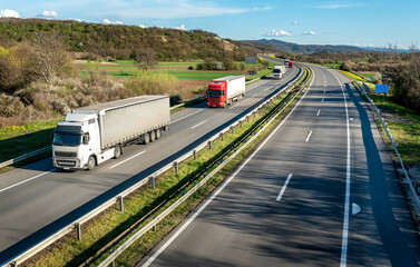 Highway transport. Transportation Trucks in lines passing on a rural countryside highway under a beautiful blue sky