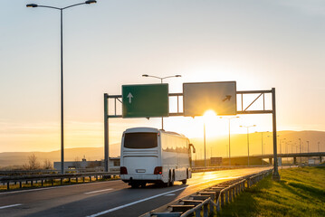 White Modern comfortable tourist bus driving through highway to bright sunny sunset. Travel and coach tourism concept. Trip and journey by vehicle © Ivan