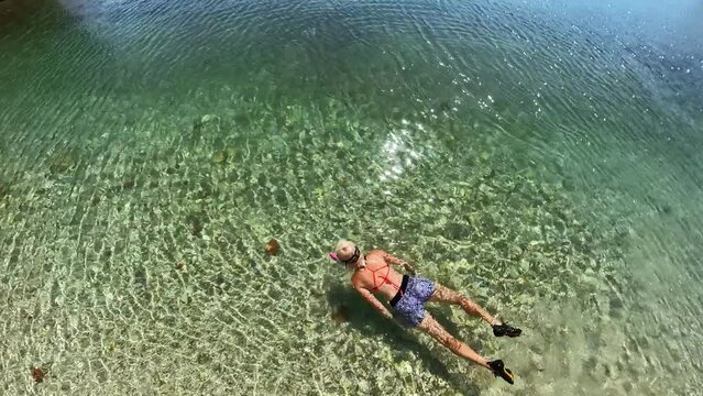 drone view of woman swimming in beach of Ksamil Islands. Ksamil offer distinct ambiance and appeal, providing visitors with a chance to experience a diverse range of natural wonders in close proximity