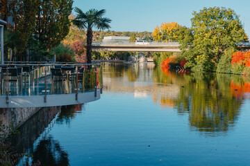Fototapeta premium River On Sunset. Townhouses Buildings And Multi-floor Home At Waterfront. Sunset On River In City. Suburb Houses And Residential Building Near River In Europe. House In Nature On Shore On Sunset.