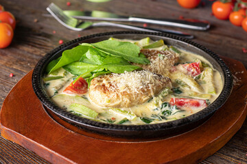 Cutlets in sauce with vegetables, sprinkled with parmesan on wooden board, Closeup