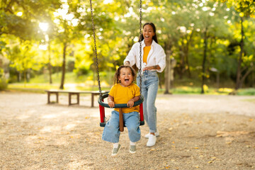 Asian Mom Riding Baby Daughter On Swing At Playground Outside