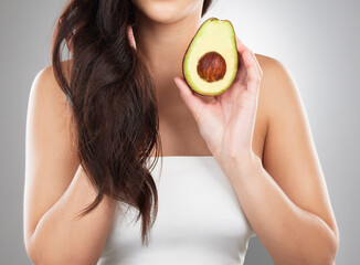 Hair care, wellness and woman with an avocado in a studio for a natural, organic or health mask. Self care, beauty and closeup of a female model with a fruit for a hair treatment by a gray background