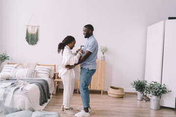 Fototapeta premium Cheerful black couple standing together in bedroom