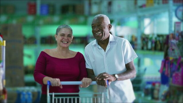 Happy diverse customers smiling inside grocery business store with shopping cart