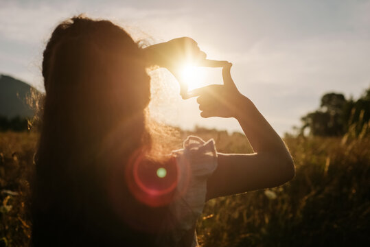 Close up of preteen girl making frame gesture at amazing warm sunset in beautiful summer park. Concept of seeing world as different. Business planning. Little child shows fingers frame symbol