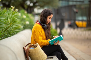 Side of young woman sitting with book and pen