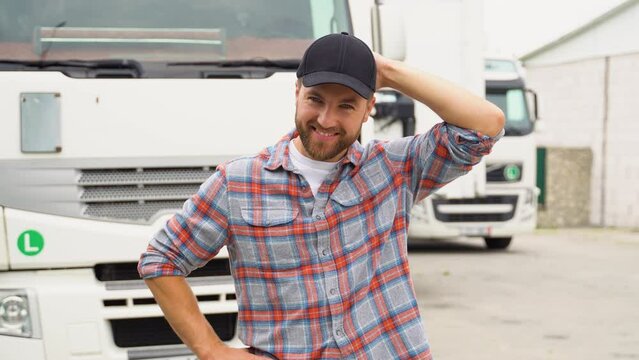 Portrait of professional bearded truck driver in casual clothes standing by his truck. Transportation services