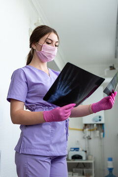 Young woman doctor looking at xray radiography images at clinic. Physician, surgeon reviewing scan of patient bones, screening test result. Medical checkup, healthcare, radiology concept.
