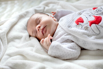 Newborn baby lying covered with white blanket.