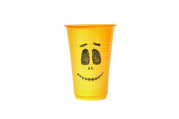 An orange cup is decorated with a scary face on a white table. Decorating a Halloween party with your own hands. Halloween cocktails.