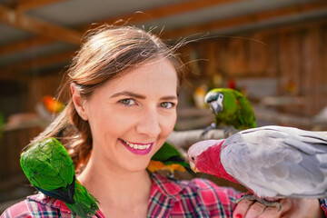 Young woman with many colourful parrot birds around, sitting on her shoulder © Lubo Ivanko