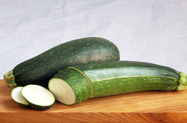 Fresh zucchini cut into slices on a wooden board.