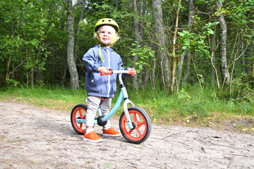 Fototapeta na wymiar Little boy riding his balance bike in the forest.
